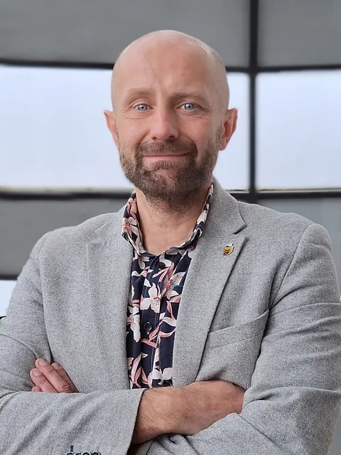 Marcin Świtoniak w szarej marynarce, prelegent pokazu maszyn Czajkowski.